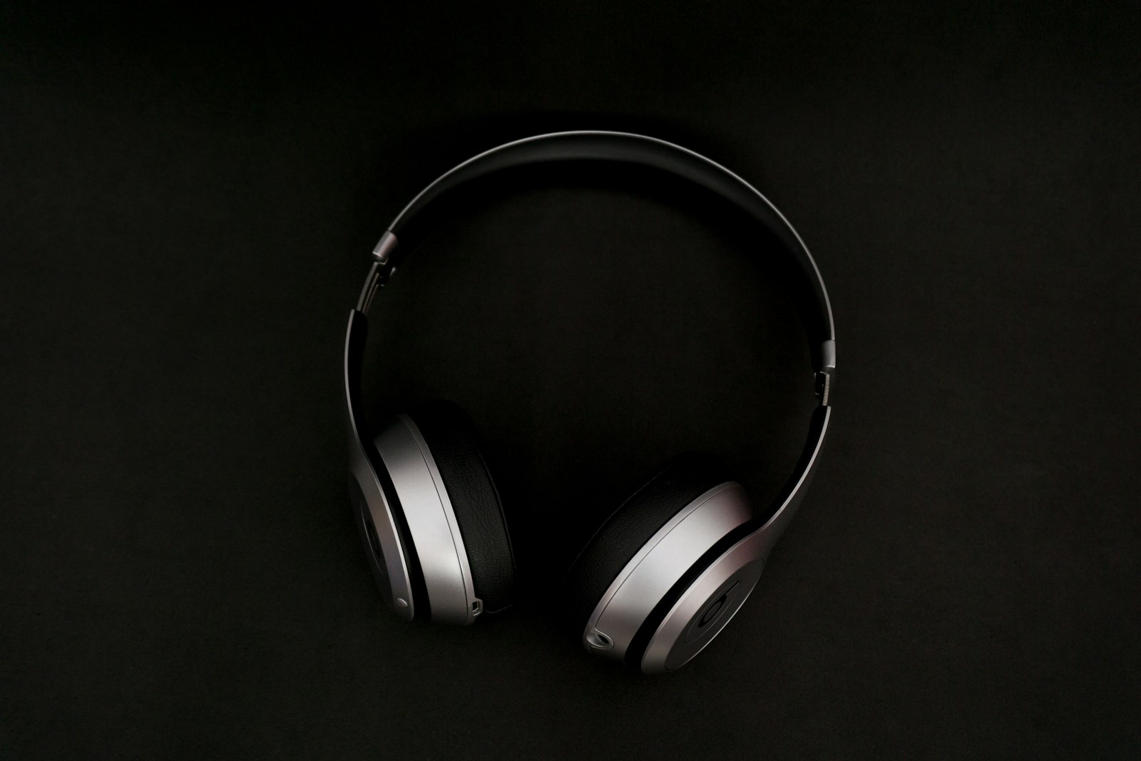Silver and black over-ear headphones on a black background.
